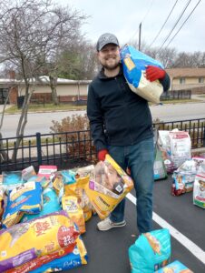 Volunteer holding dog food donations at Tackle Pet Hunger Collection day