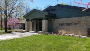 Brukner Nature Center Interpretive Building exterior with stone façade, green lawn, and blooming redbud trees in spring